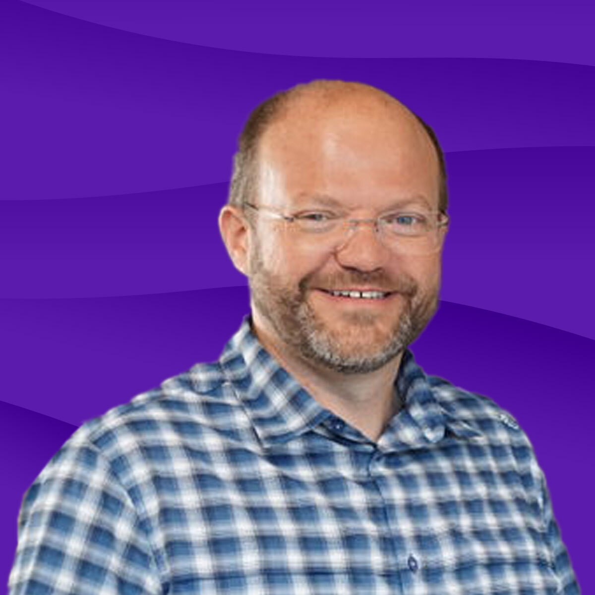 Lächelnder Mann mit Brille in kariertem Hemd vor lila Hintergrund.